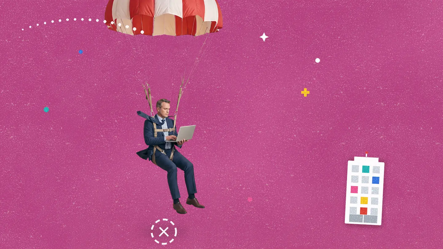 A businessman in a suit descends by a red-and-white parachute while typing on a laptop mid-air, drifting toward a small office building, on a pink background.